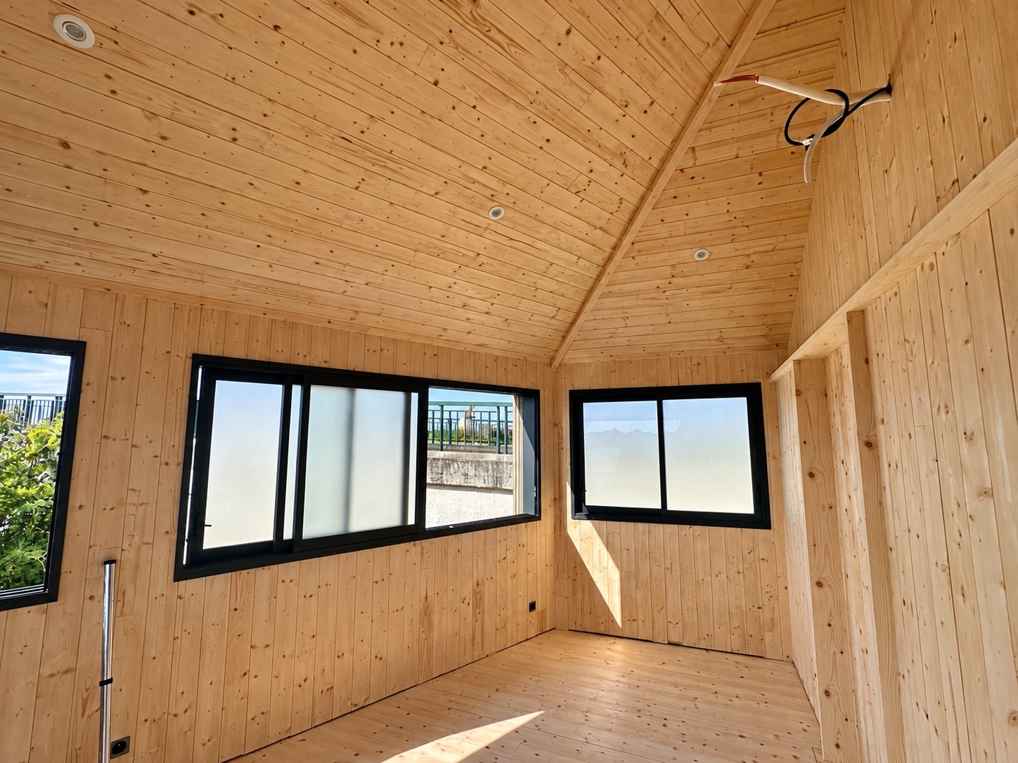 Intérieur en lambris d’épicéa avec fenêtres en aluminium noir.